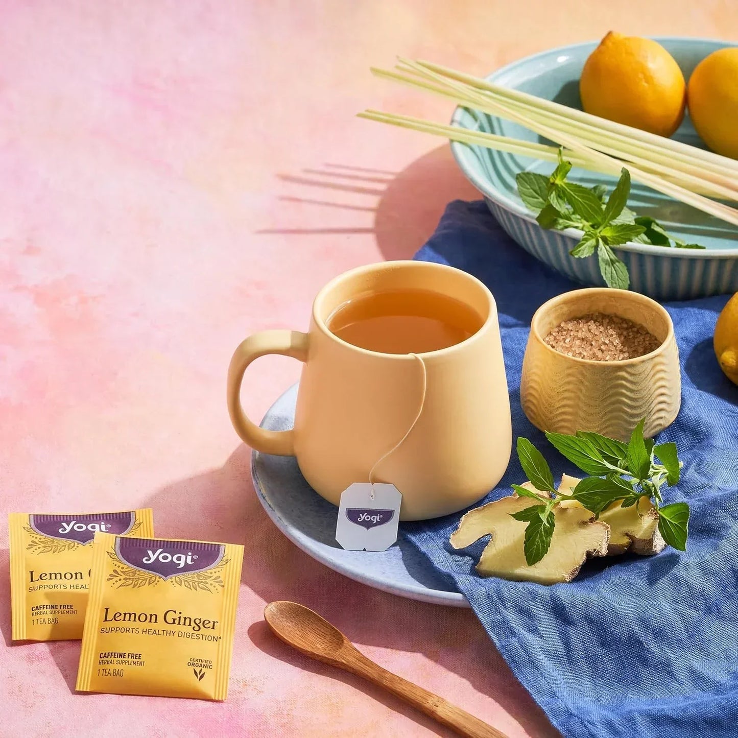 Yogi Lemon Ginger tea in mug with fresh ginger, mint, lemons, and organic tea bags for healthy digestion