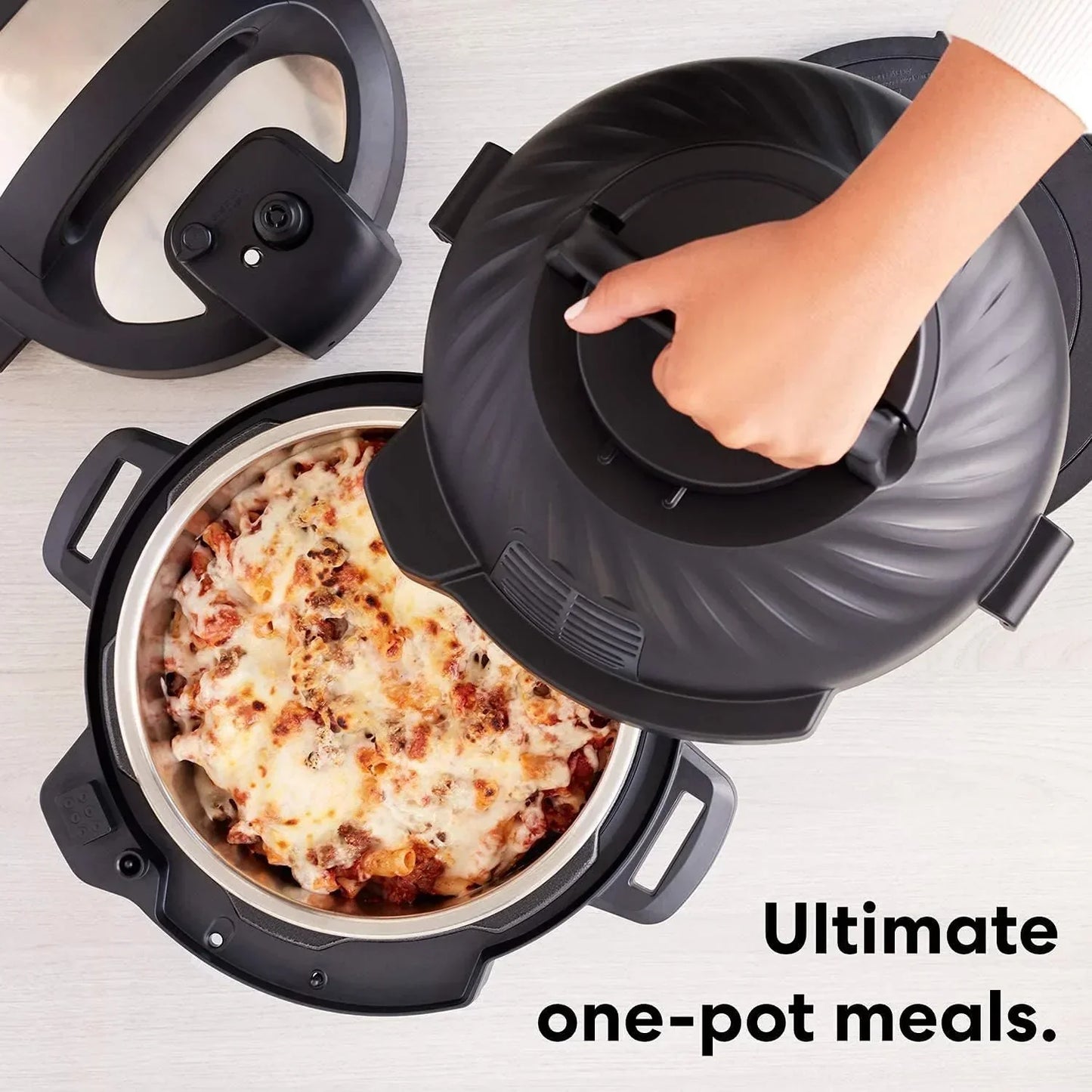 Hand lifting lid off pressure cooker with cheesy pasta inside, perfect for one-pot meals.