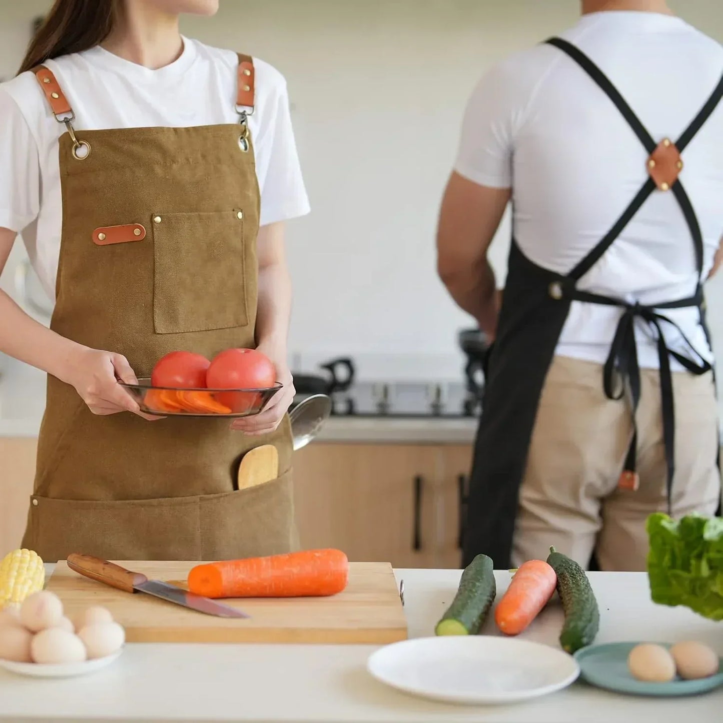 Couple in aprons preparing fresh vegetables in a modern kitchen with cookware and tools