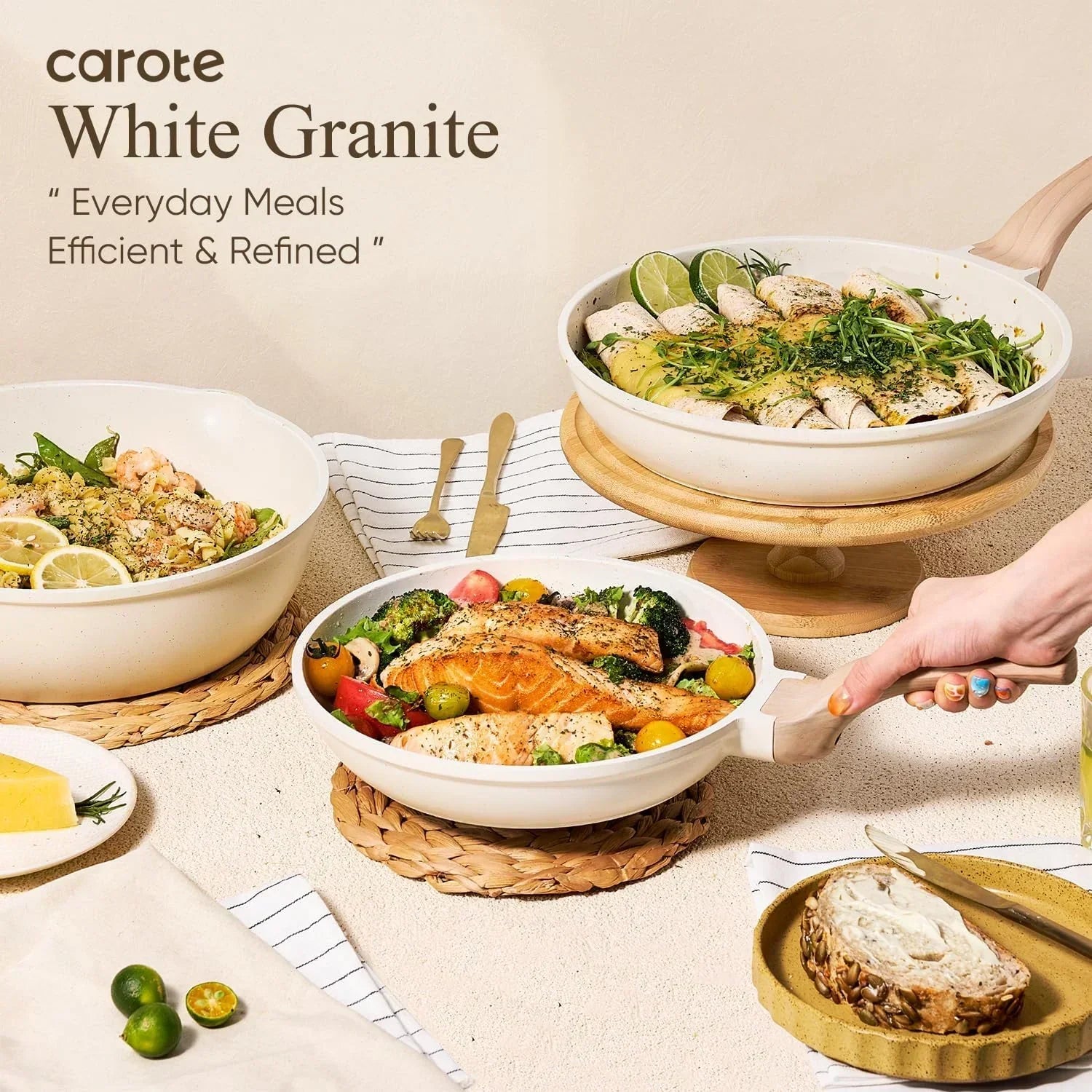 White granite cookware with assorted cooked meals, fresh vegetables, bread, and gold utensils on a kitchen table.