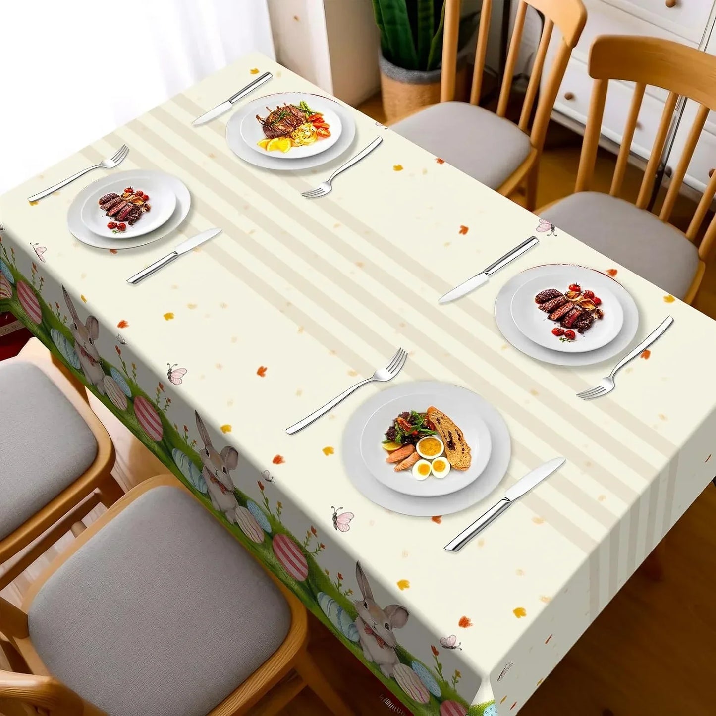 Easter-themed tablecloth with bunnies, eggs, and stripes, set for dining with plates and cutlery