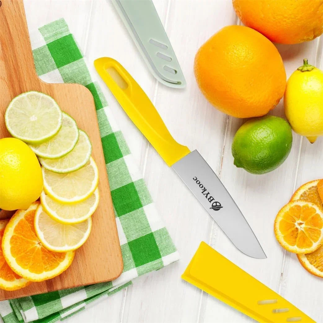 Yellow-handled paring knife with citrus fruits on wooden cutting board, kitchen tools, and green checkered napkin