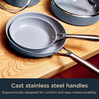Stacked gray nonstick frying pans with cast stainless steel handles on wood countertop