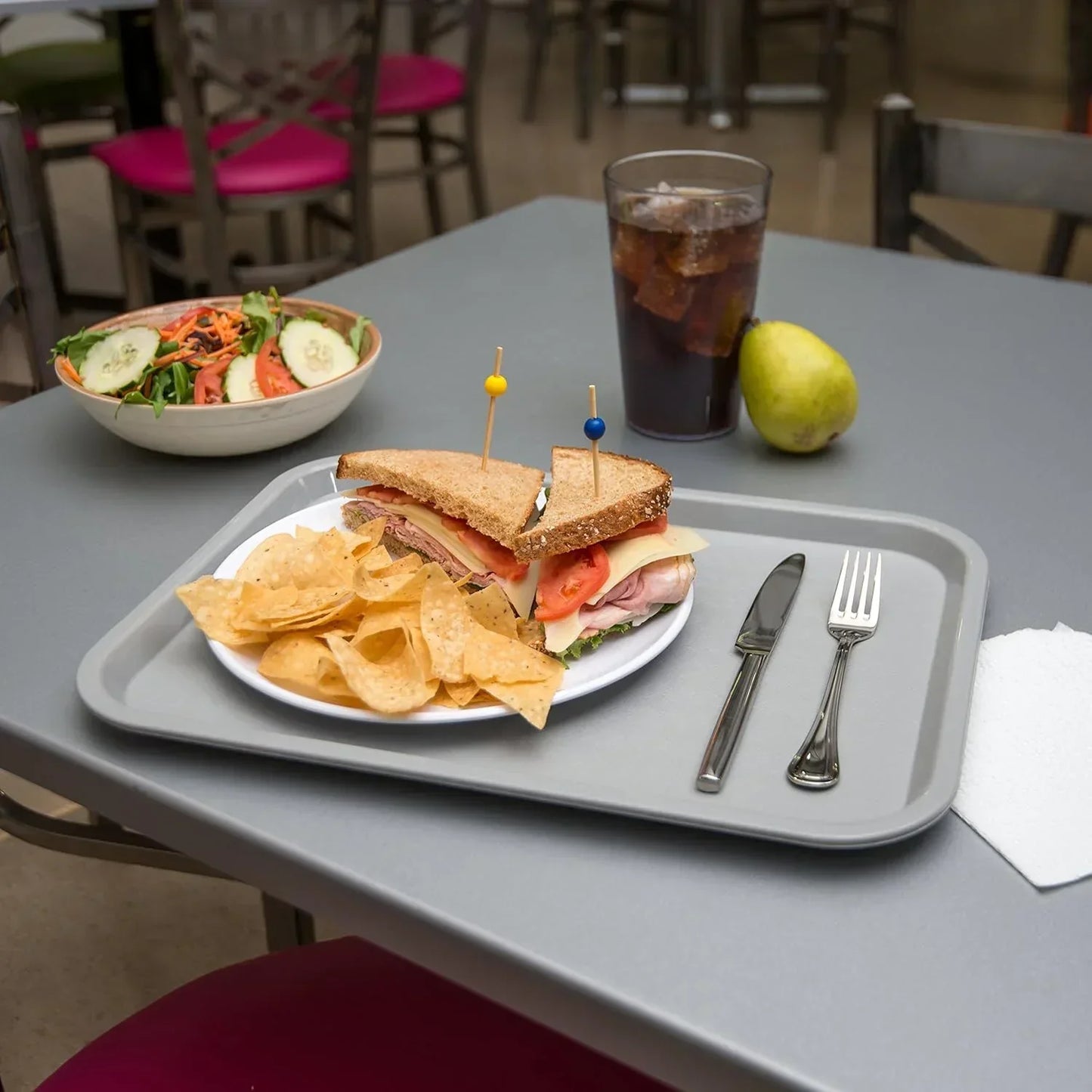 Delicious sandwich with chips, salad, and soda on a gray tray for casual dining