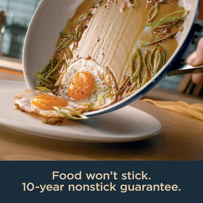 Nonstick frying pan with sunny-side-up eggs and greens sliding onto plate, 10-year guarantee