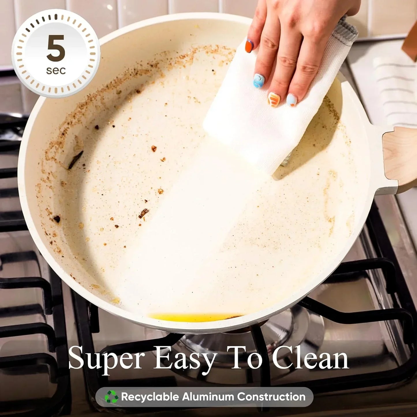 Hand wiping clean a white nonstick frying pan with food residue on a gas stove