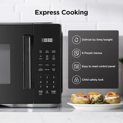 Black digital microwave oven with control panel, quick start features, and baked potatoes on kitchen counter.