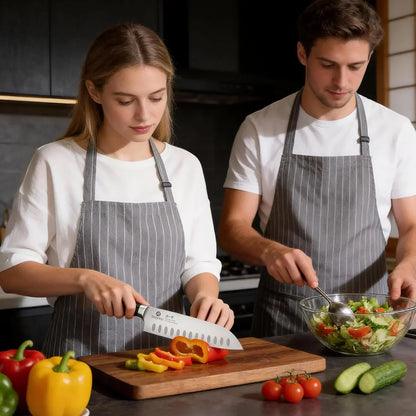 Couple in kitchen aprons slicing bell peppers and preparing fresh vegetable salad