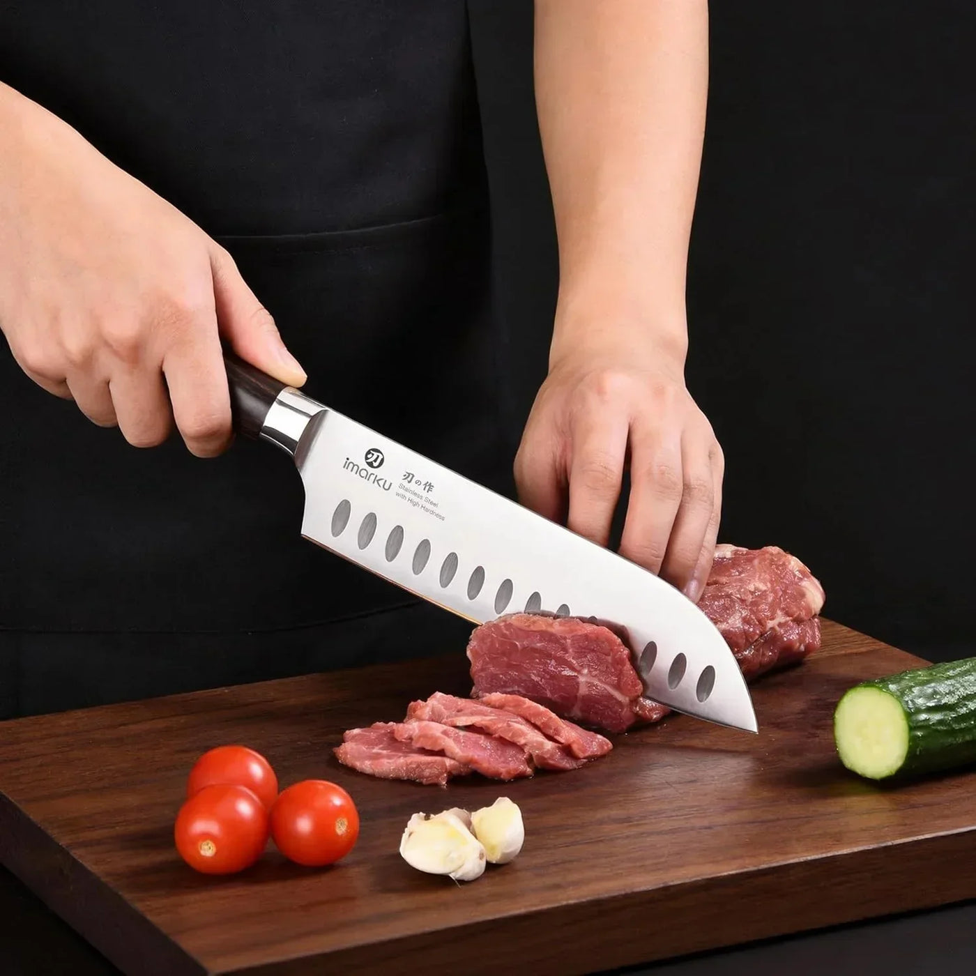 Chef slicing raw beef with a stainless steel kitchen knife on a cutting board, tomatoes, garlic, and cucumber nearby.