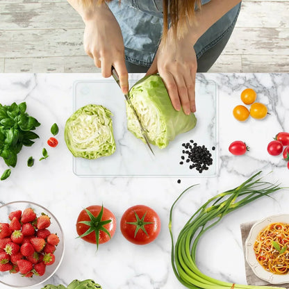 Woman slicing cabbage on glass cutting board with fresh produce and pasta nearby for meal prep