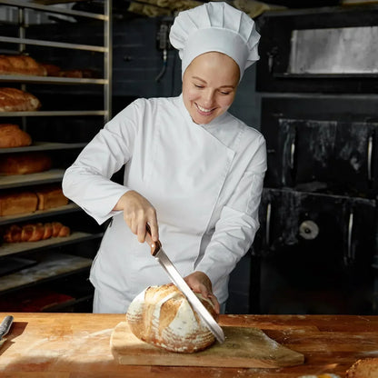 Chef slicing fresh artisan bread with serrated knife in bakery kitchen