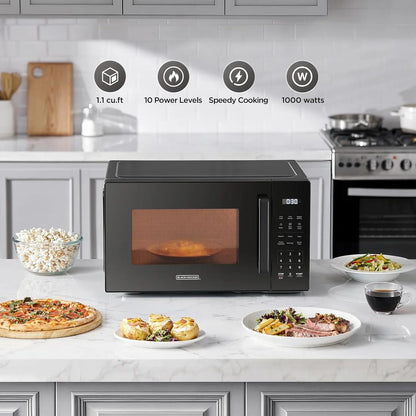 Black countertop microwave oven with digital controls on a kitchen marble counter, surrounded by prepared food.