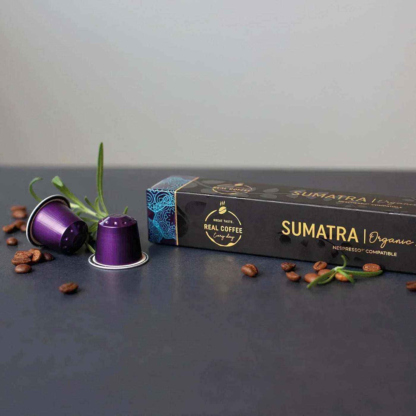 Sumatra organic coffee pods, Nespresso compatible, with purple capsules and roasted beans on dark surface