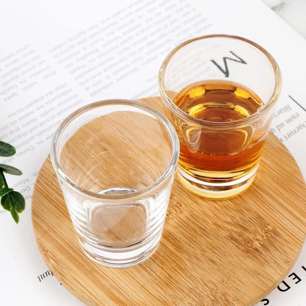 Clear glass shot glasses with amber liquid on wooden coaster, ideal for kitchen barware and serving
