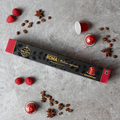 Roma Italian espresso coffee pods, Nespresso compatible, with raspberries, star anise, and coffee beans on gray surface