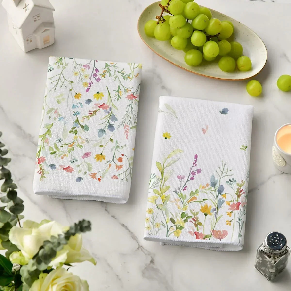Floral kitchen towels with watercolor wildflowers on marble countertop, paired with green grapes and home decor