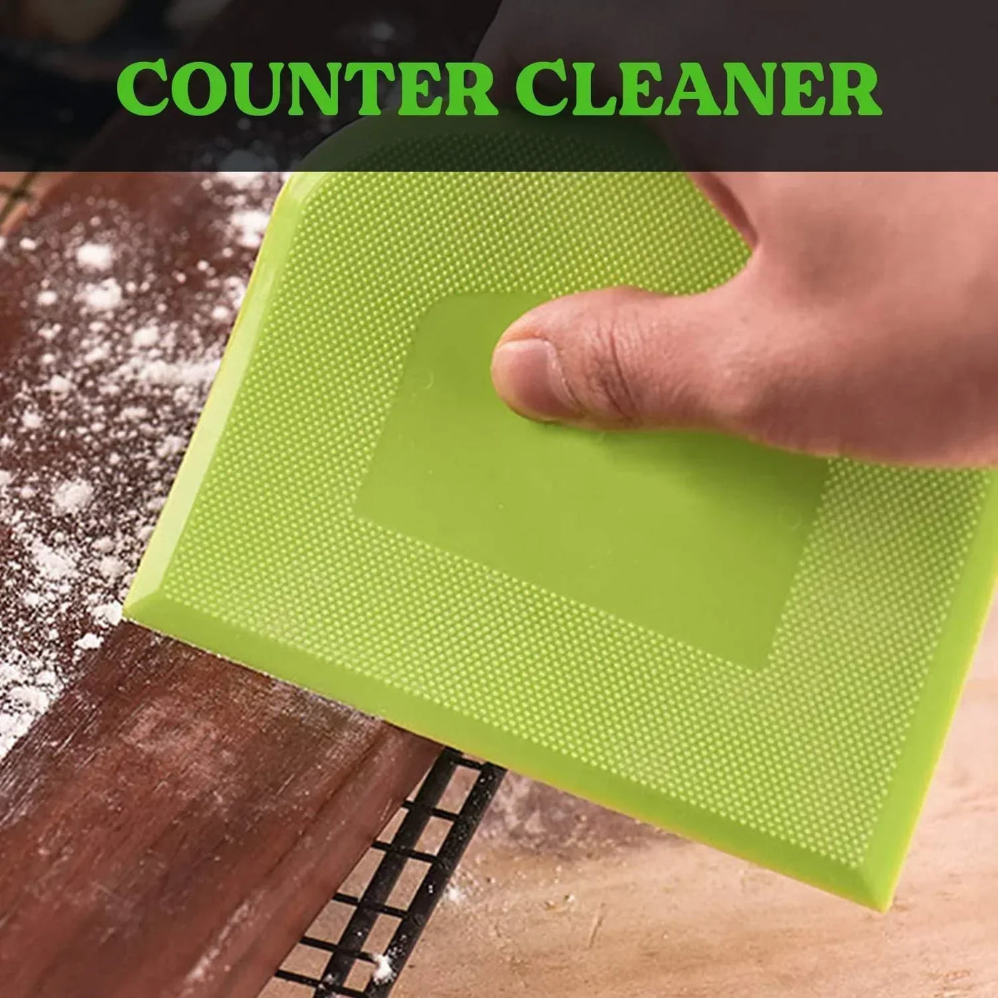 Green silicone counter cleaner scraping flour off wooden kitchen surface
