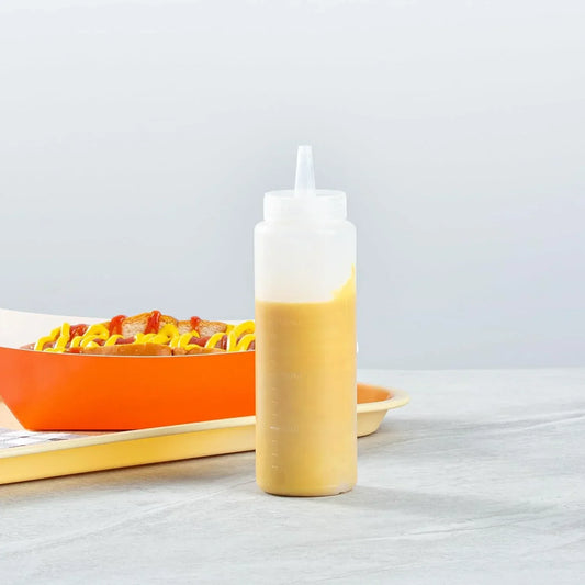 Clear squeeze bottle with mustard next to hot dogs in orange tray, kitchen condiment dispenser for cooking and serving