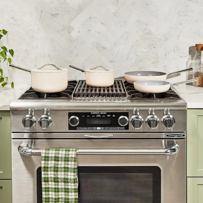 Modern kitchen stove with white cookware set, frying pans, and saucepans on countertop