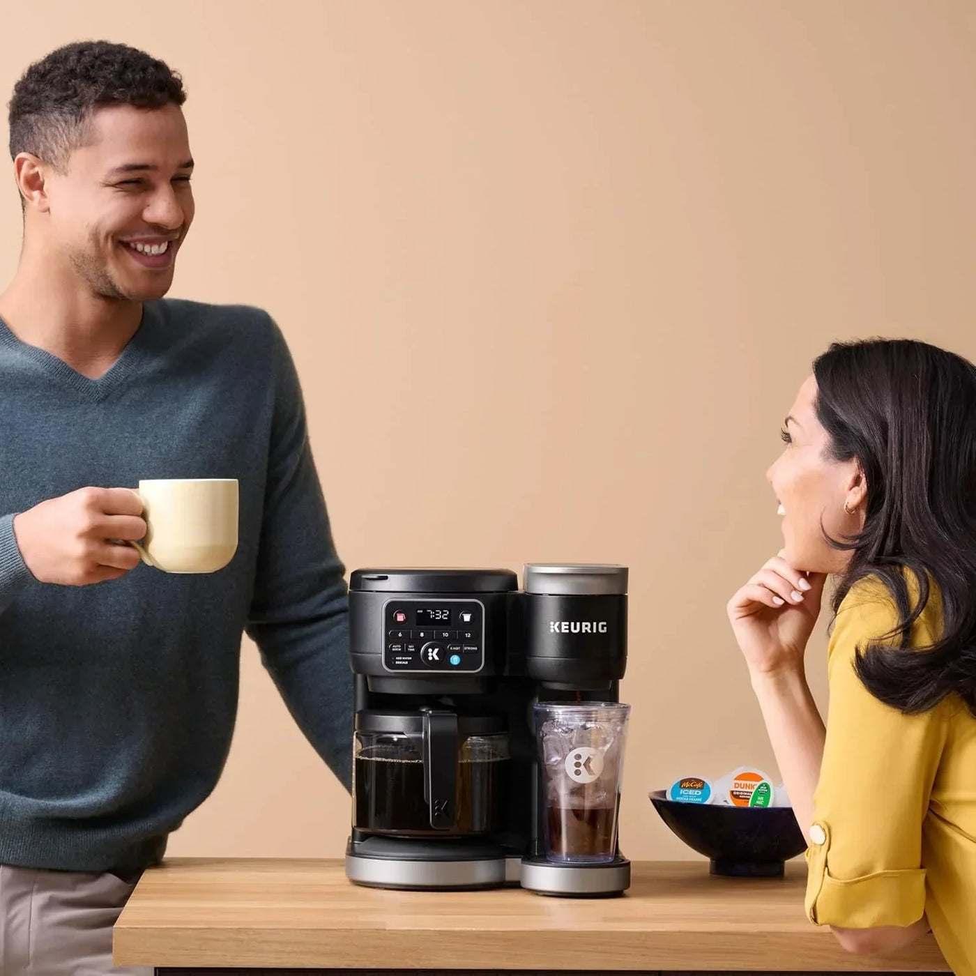 Keurig coffee maker brewing hot and iced coffee with couple enjoying drinks at kitchen counter