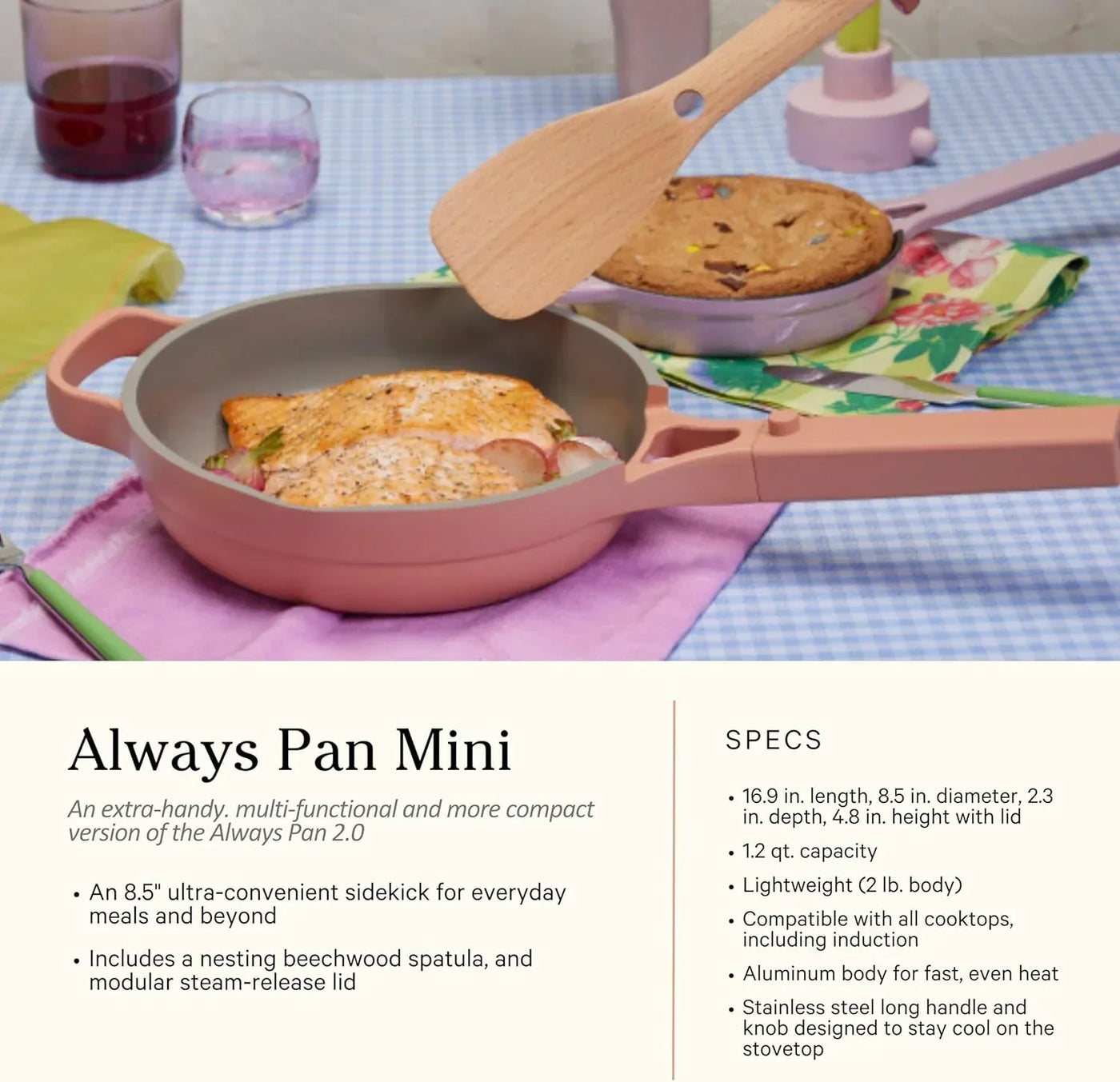 Pink Always Pan Mini with salmon and veggies, wooden spatula, and cookie in background on checkered tablecloth