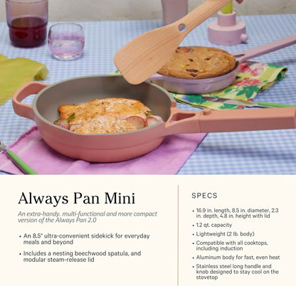 Pink Always Pan Mini with salmon and veggies, wooden spatula, and cookie in background on checkered tablecloth
