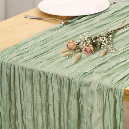 Mint green pleated table runner with dried roses and baby's breath, styled on wooden table with white plate and fork