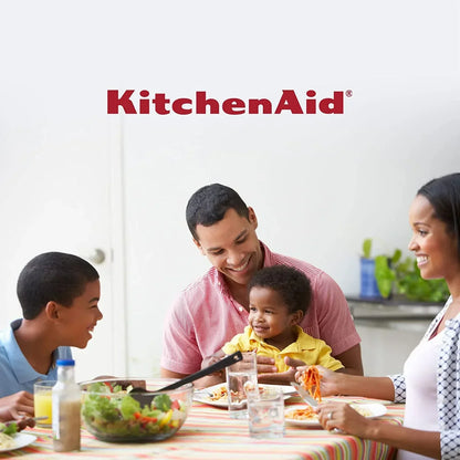 Family enjoying meal together with KitchenAid logo, featuring pasta, salad, and tableware in bright kitchen setting