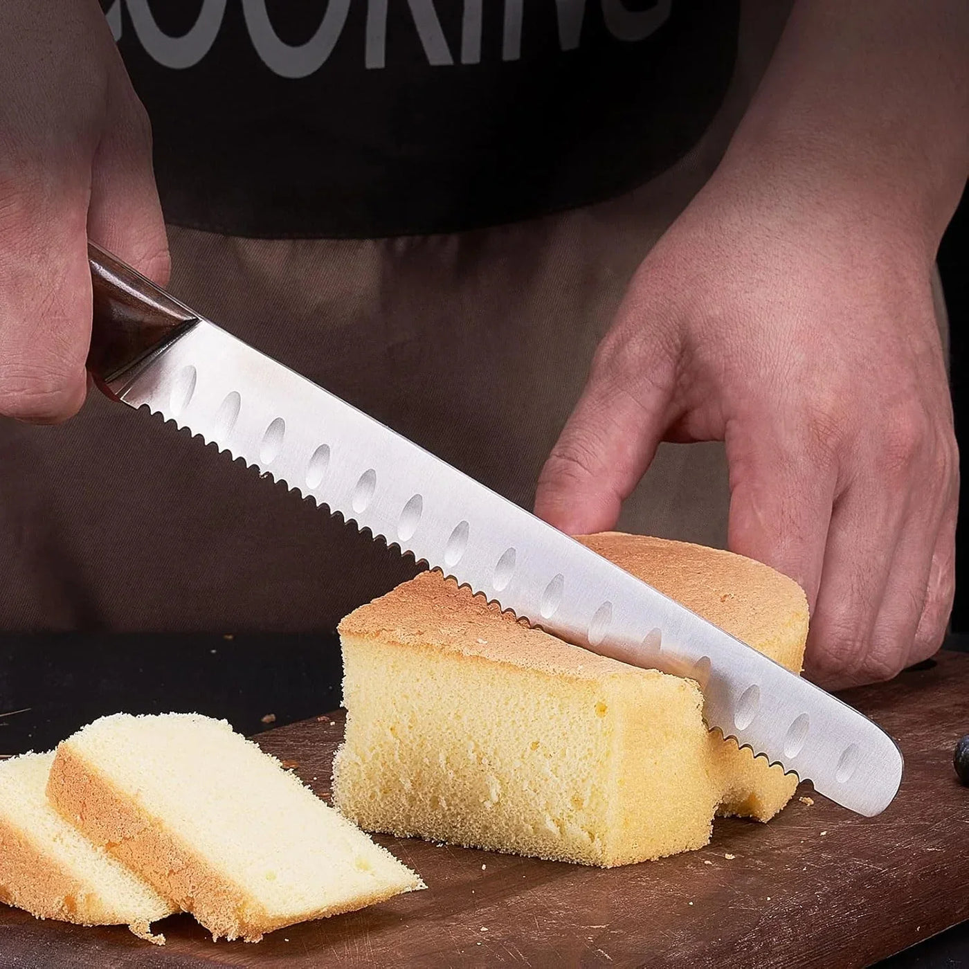 Slicing sponge cake with serrated bread knife on wooden cutting board