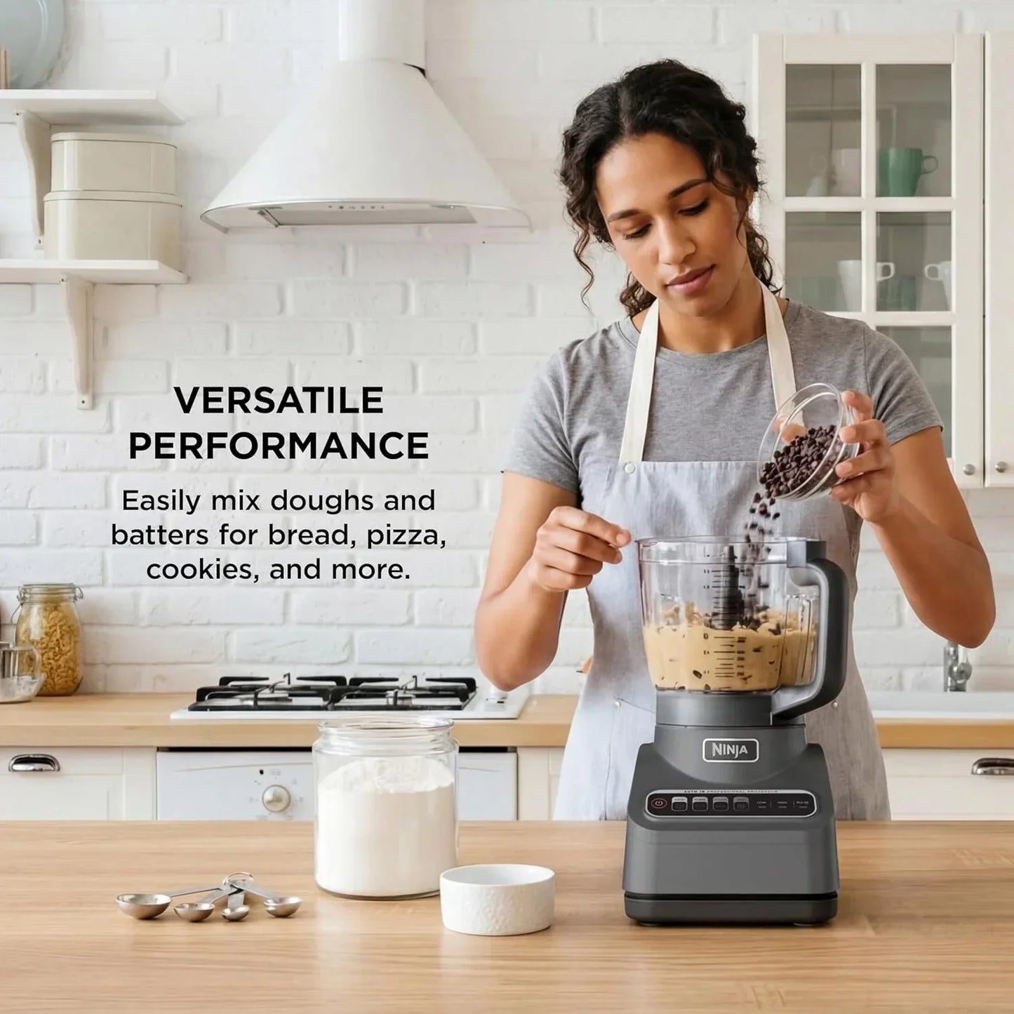 Woman adding chocolate chips to Ninja blender for cookie dough in bright kitchen