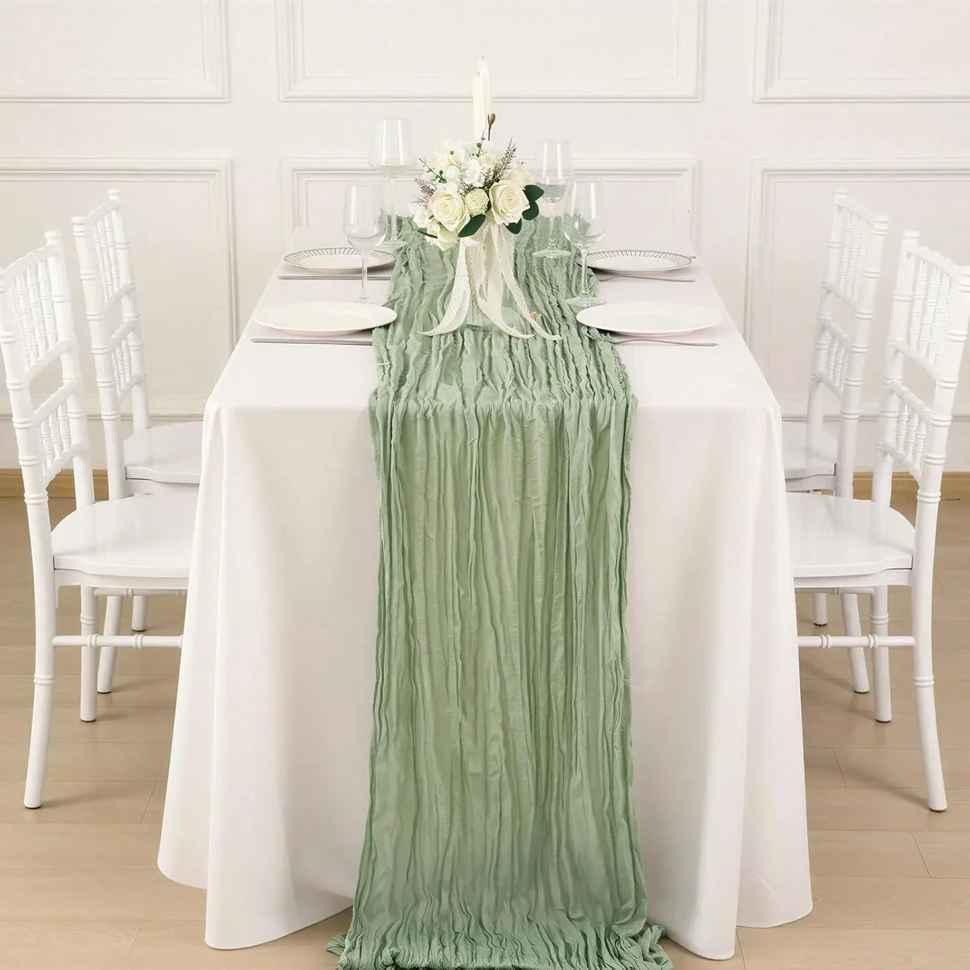 Mint green ruched table runner on white dining table with floral centerpiece, perfect for elegant table linens and wedding decor.