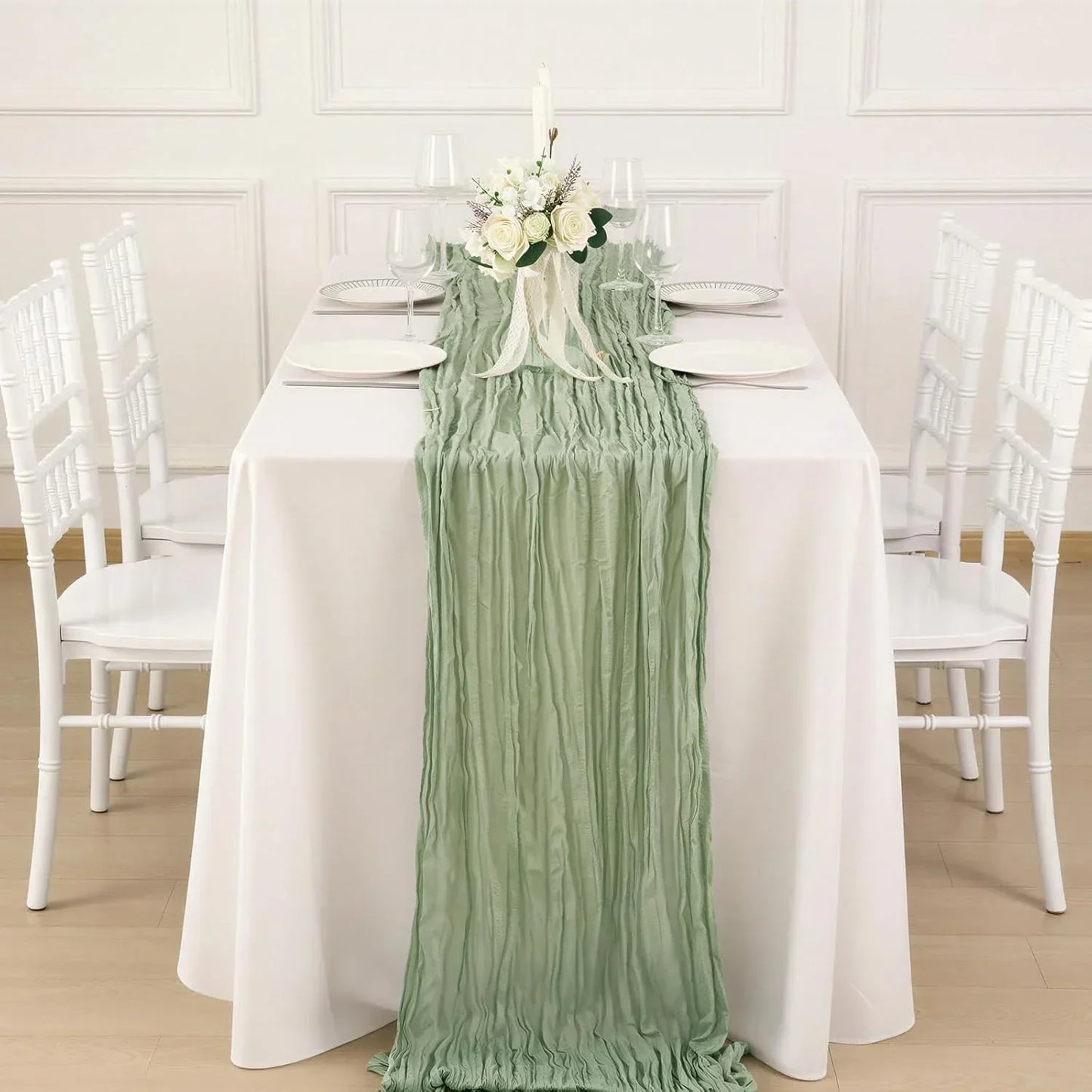 Mint green ruched table runner on white dining table with floral centerpiece, perfect for elegant table linens and wedding decor.