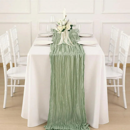 Mint green ruched table runner on white dining table with floral centerpiece, perfect for elegant table linens and wedding decor.