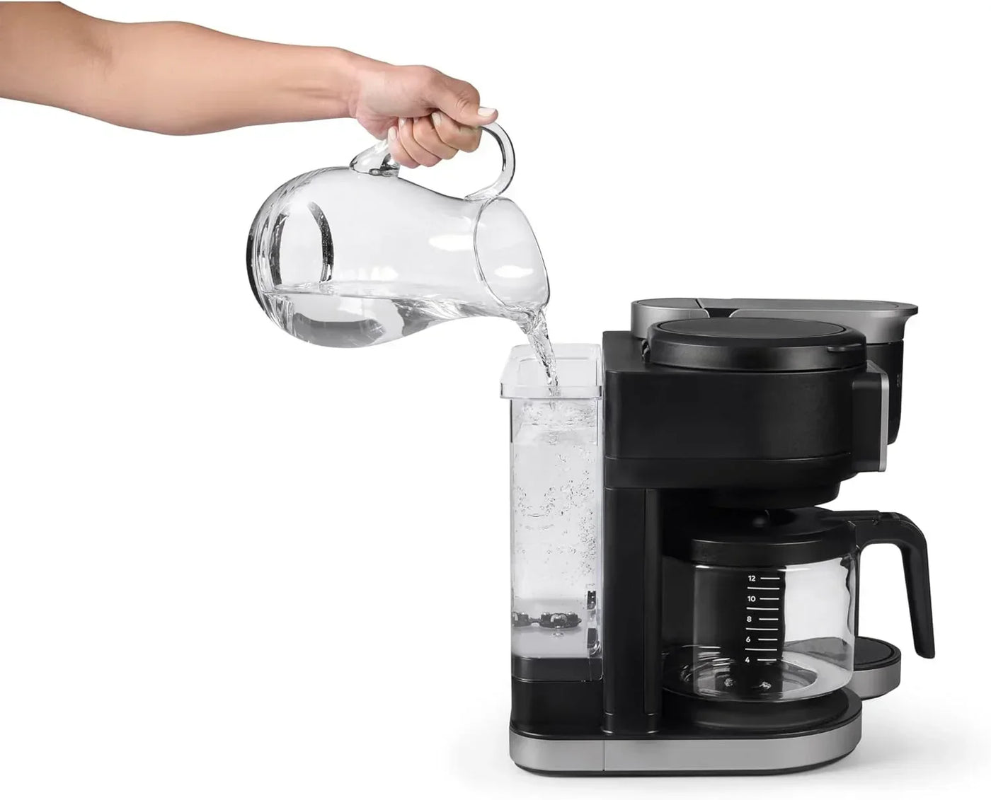 Hand pouring water into coffee maker with glass carafe and black base