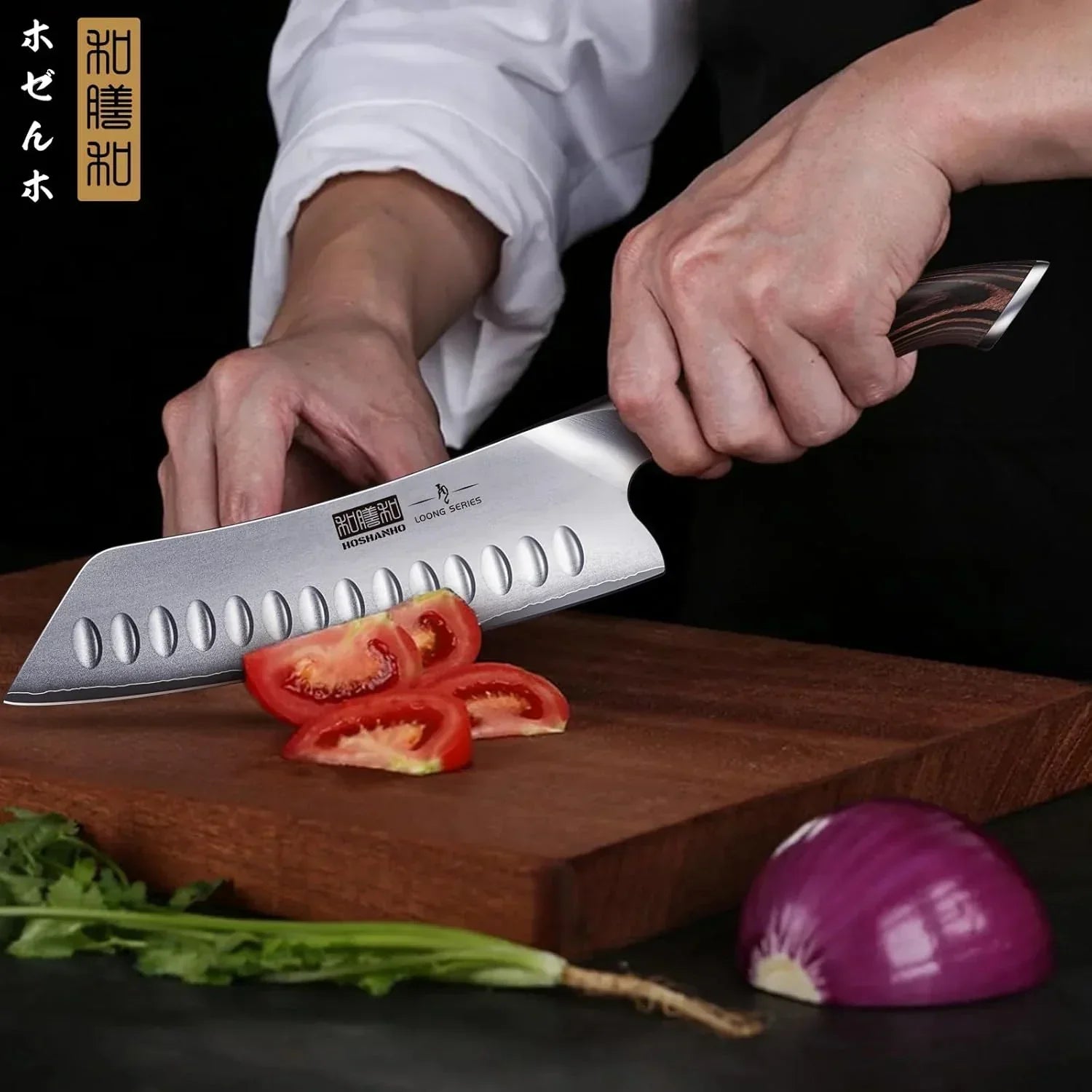 Chef slicing tomato with sharp kitchen knife on wooden cutting board, next to onion and herbs