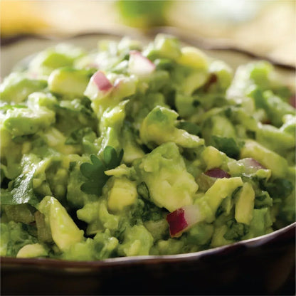 Fresh homemade guacamole with avocado, red onion, and cilantro in a rustic bowl