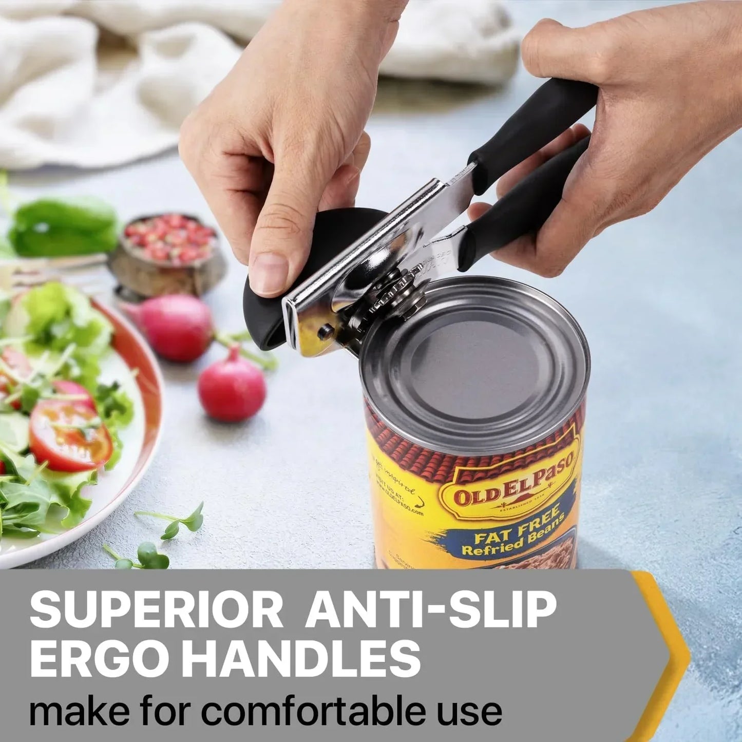 Ergonomic can opener with anti-slip handles opening a can of refried beans beside a fresh salad