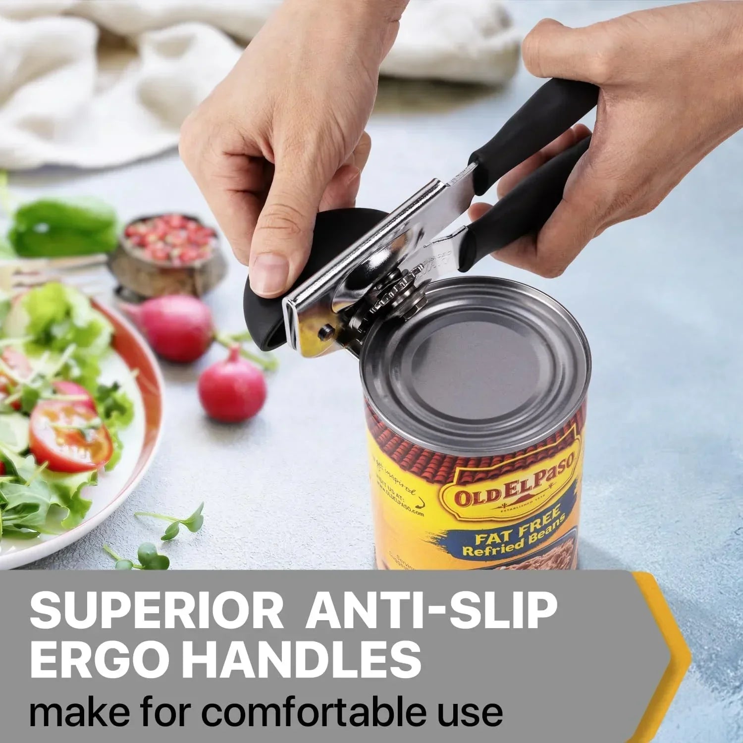 Ergonomic can opener with anti-slip handles opening a can of refried beans beside a fresh salad